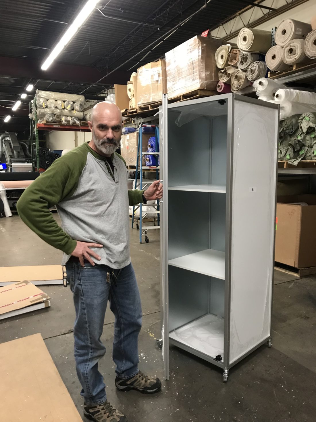 man standing next to mobile whiteboard cube cabinet shown with door open